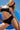 Woman in a black Sensation underwear set against a blue background